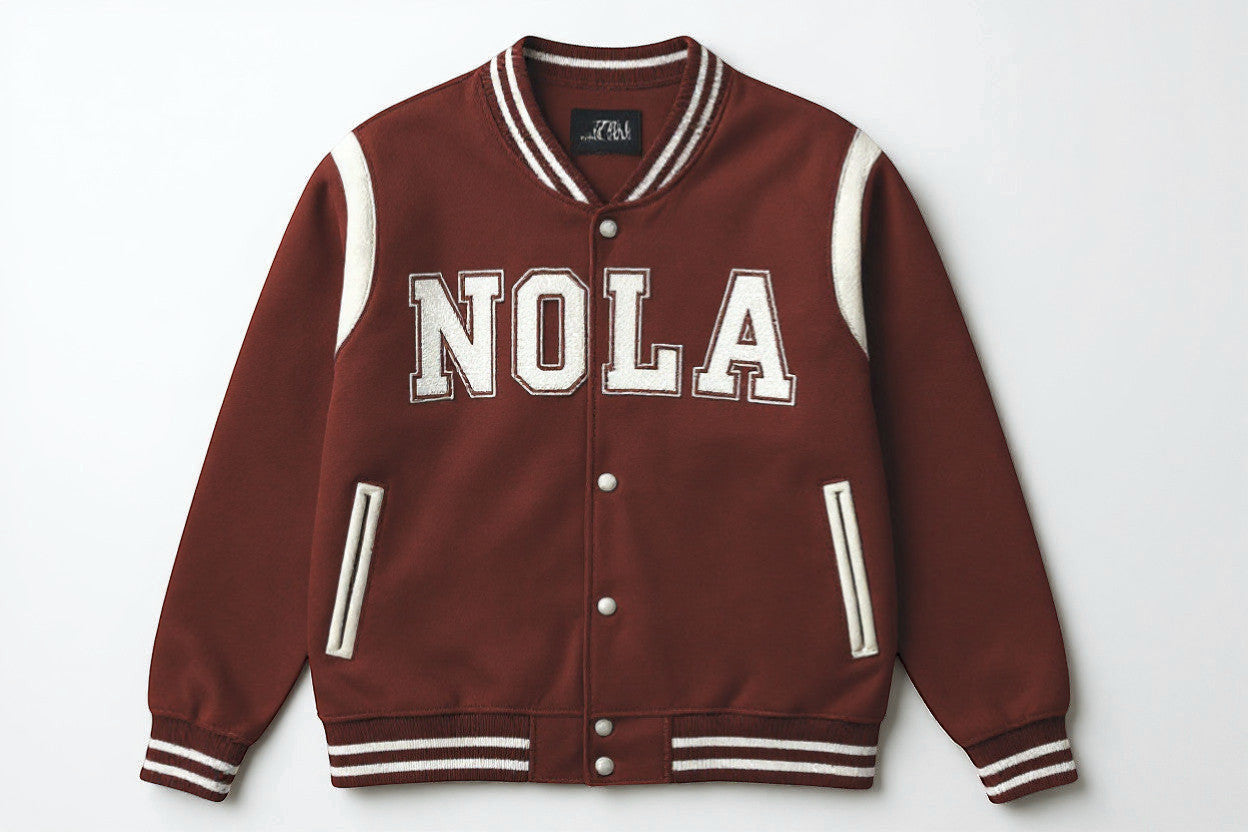 Rejecting Retail Studio personalized women's red varsity bomber jacket with white "NOLA" embroidery and cream accents.