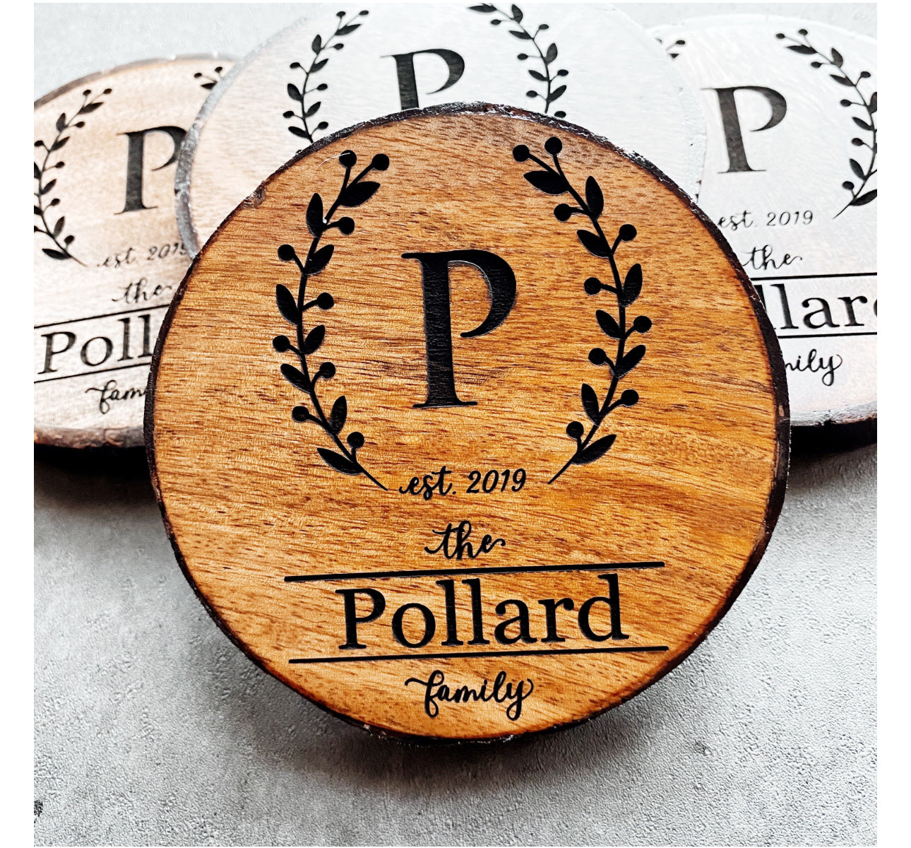 Close view of personalized wreath monogram wood coasters showing engraving detail and natural grain.