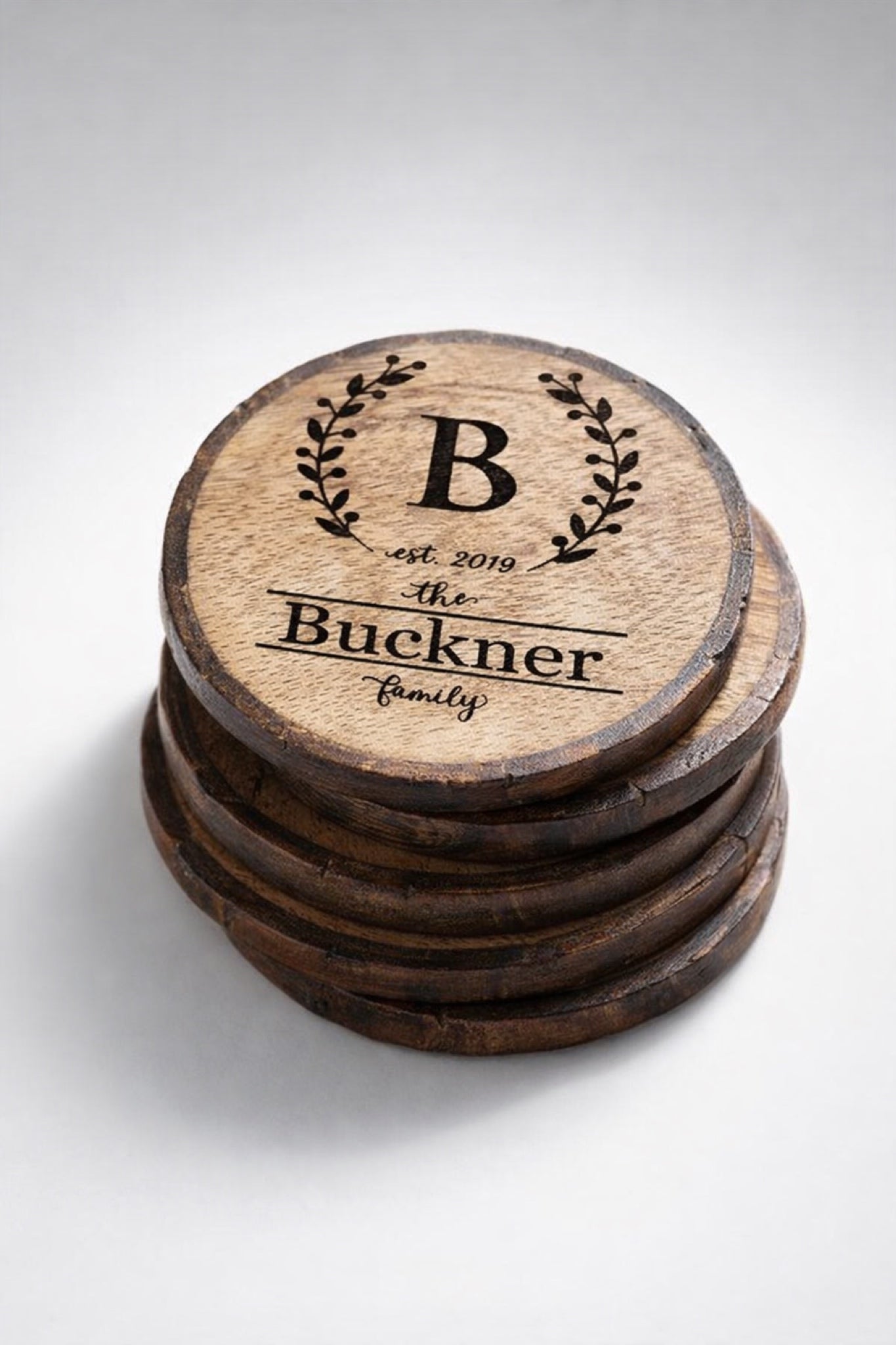Set of four personalized engraved wood slice coasters stacked to show thickness and quantity.