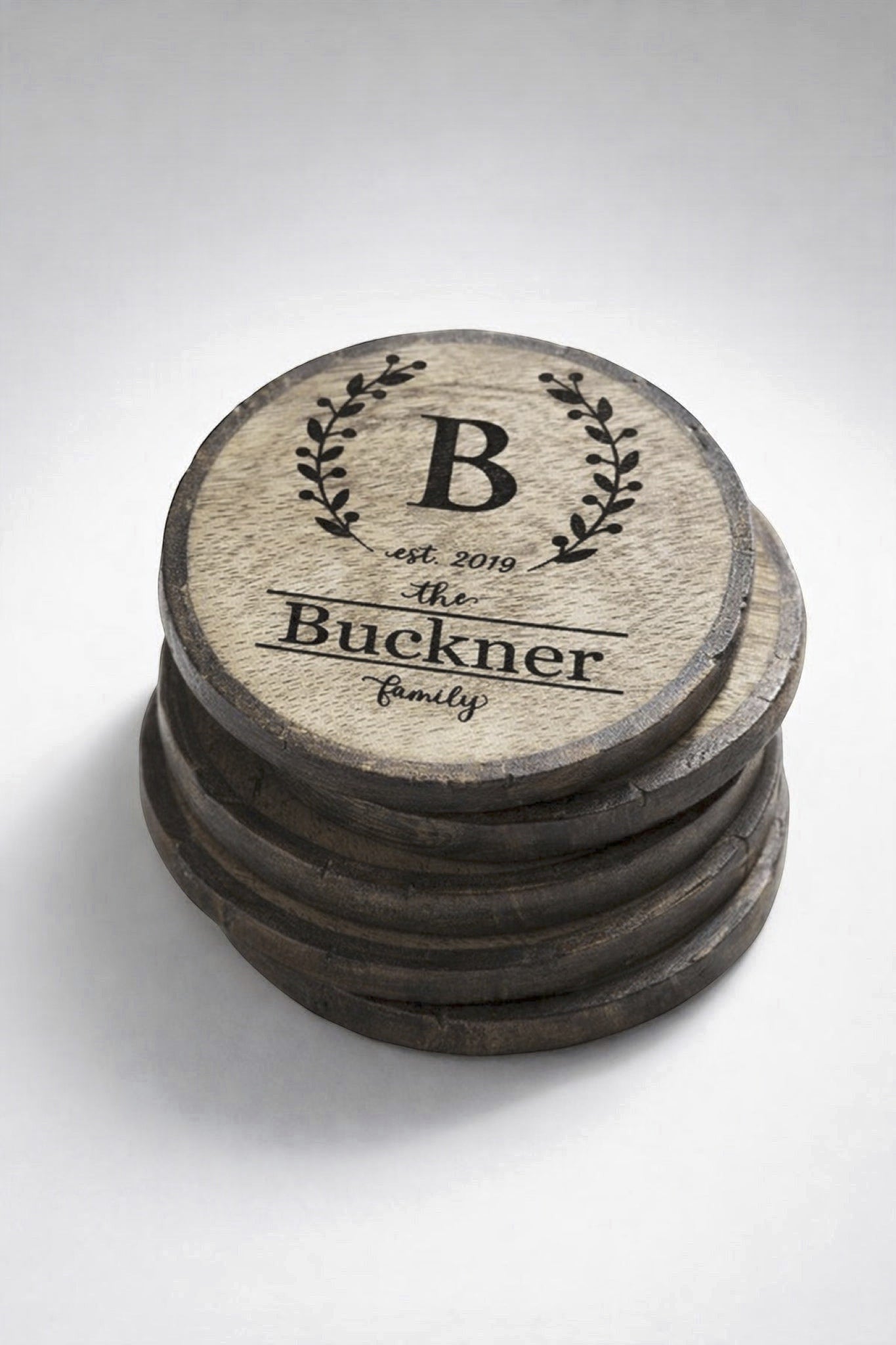Set of four personalized engraved wood slice coasters stacked to show thickness and quantity.