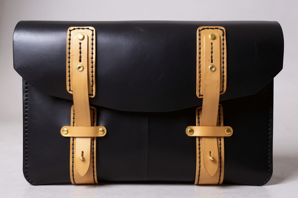 Rejecting Retail Studio black leather portfolio bag with tan accents and buckle closures. Hand-sewn document holder.