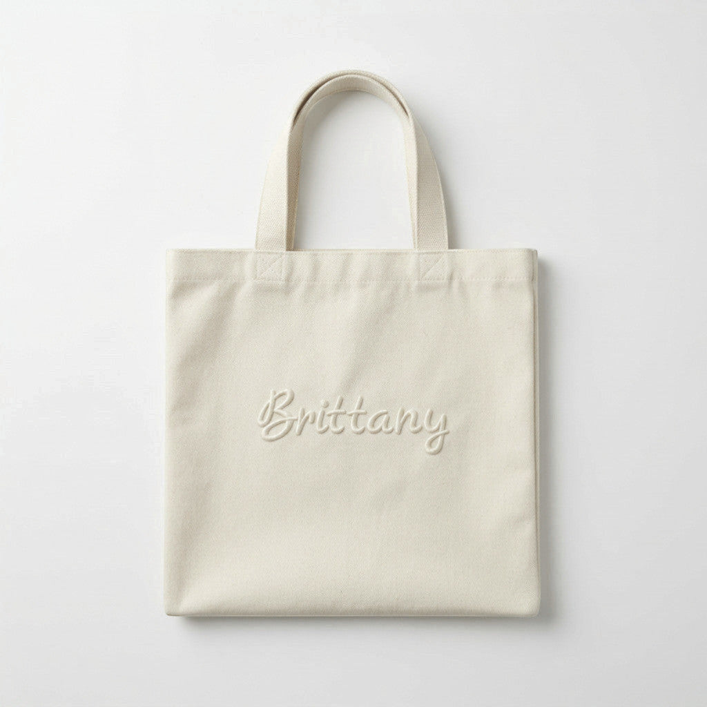Rejecting Retail Studio natural canvas tote bag with 3D puff embroidered custom name in script font.