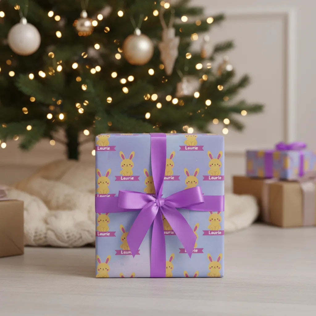 Rejecting Retail Studio personalized gift wrap with a lavender background, featuring a repeating pattern of yellow bunnies with pink ribbons and the name "Laurie".