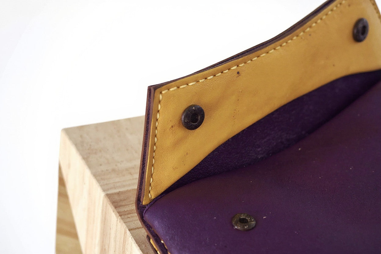 Rejecting Retail Studio handmade leather wristlet wallet in deep purple and warm orange with magnetic snap closure.